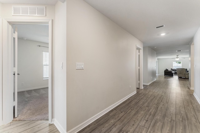 corridor with visible vents, baseboards, and wood finished floors