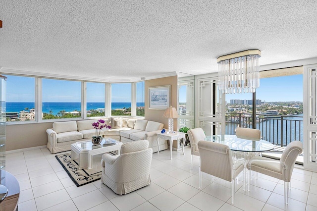 living room with tile patterned floors, a water view, a textured ceiling, and a chandelier