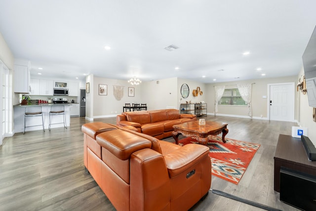 living room with light wood-style flooring, visible vents, a chandelier, and recessed lighting