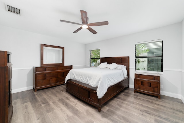 bedroom featuring a ceiling fan, baseboards, visible vents, and wood finished floors