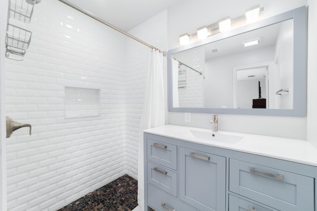 bathroom with a tile shower and vanity