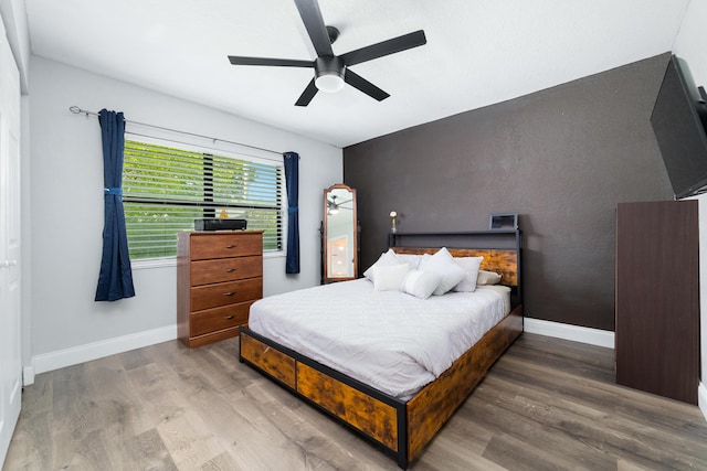 bedroom featuring ceiling fan, wood finished floors, and baseboards