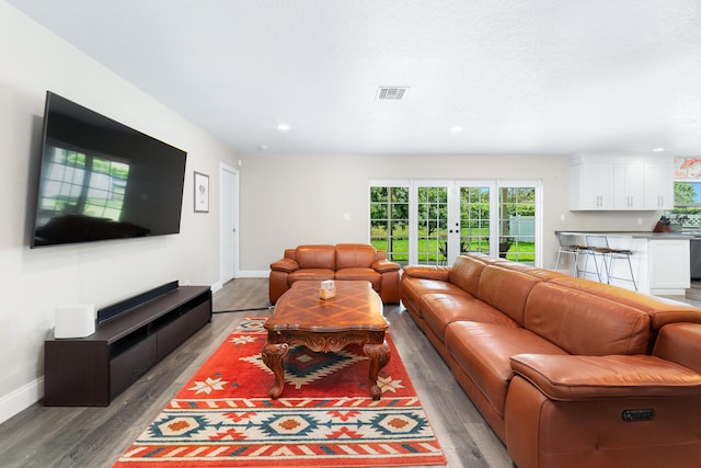 living room with french doors, light wood-type flooring, visible vents, and baseboards