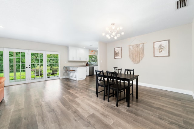 dining area featuring a chandelier, visible vents, baseboards, and wood finished floors