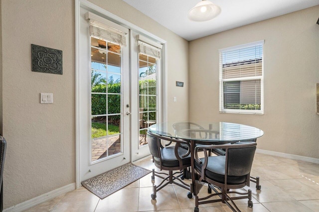 dining area with light tile patterned floors, a textured wall, french doors, and baseboards