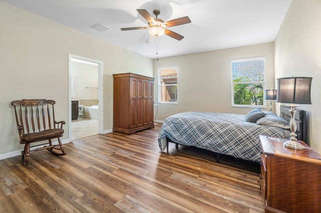 bedroom with visible vents, baseboards, ensuite bath, ceiling fan, and wood finished floors