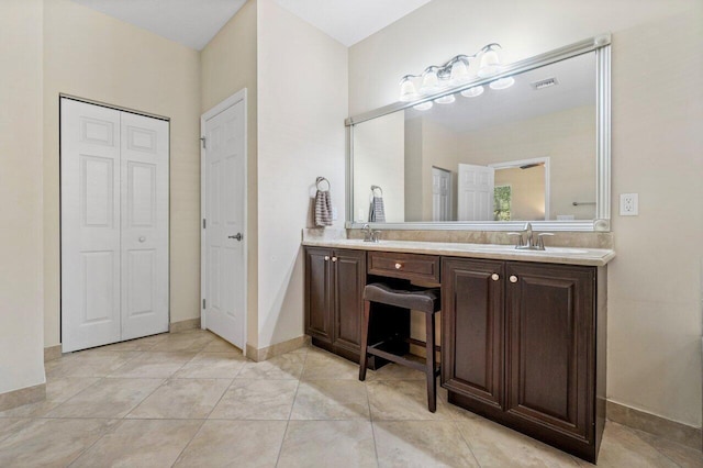 bathroom with double vanity, baseboards, visible vents, a sink, and a closet