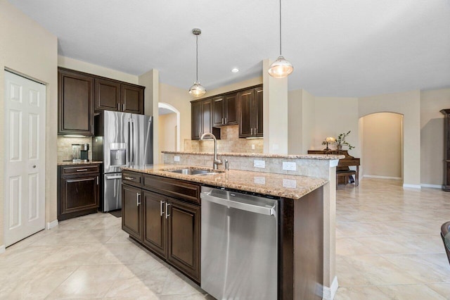 kitchen featuring dark brown cabinets, arched walkways, stainless steel appliances, and a sink