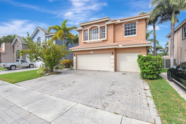 view of front facade with a garage, decorative driveway, a tile roof, and stucco siding