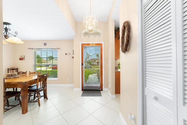 entryway featuring light tile patterned floors, a notable chandelier, and baseboards