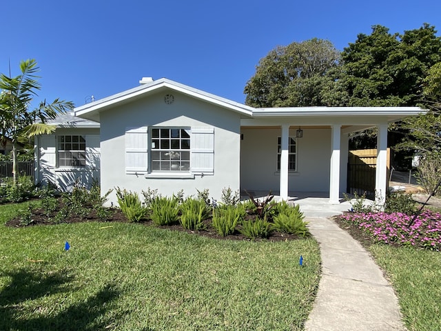 view of front of property with stucco siding, covered porch, and a front yard