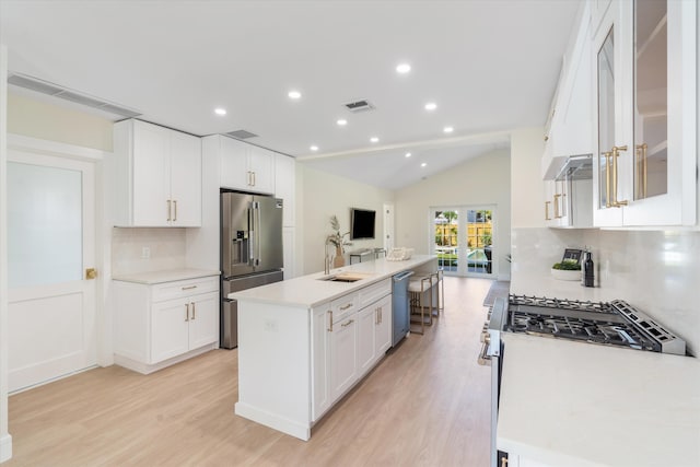 kitchen with stainless steel appliances, tasteful backsplash, light wood finished floors, vaulted ceiling, and a sink