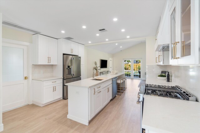 108 NW 4th Ave, Delray Beach, FL 33444 - kitchen featuring stainless steel appliances, decorative backsplash, light wood-style flooring, an island with sink, and lofted ceiling