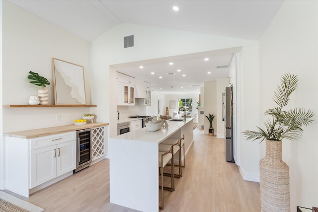 108 NW 4th Ave, Delray Beach, FL 33444 - kitchen with a sink, a breakfast bar area, vaulted ceiling, light wood-style flooring, and white cabinets