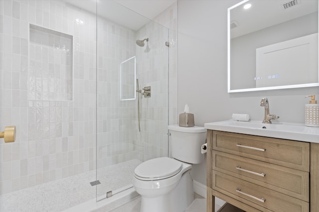 full bathroom featuring toilet, a tile shower, vanity, and baseboards