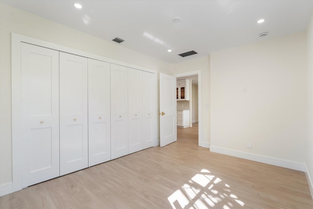 unfurnished bedroom featuring light wood-style floors, baseboards, a closet, and recessed lighting