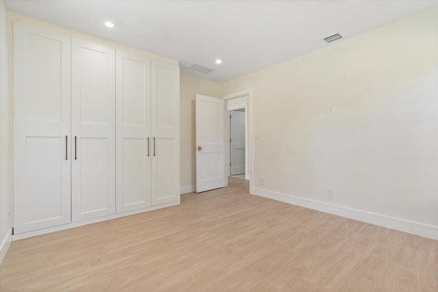 unfurnished bedroom featuring light wood-type flooring, baseboards, recessed lighting, and a closet