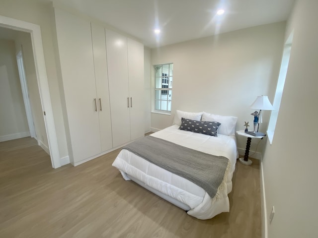 bedroom with light wood finished floors and baseboards