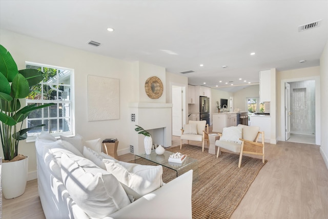 living area featuring light wood-type flooring, plenty of natural light, baseboards, and recessed lighting