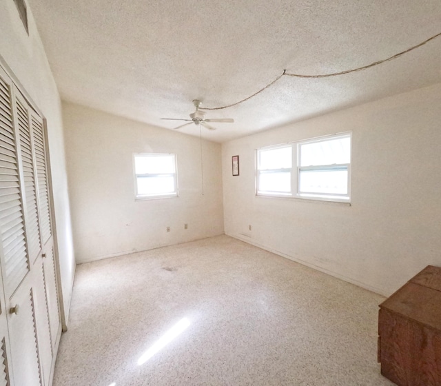 unfurnished bedroom featuring ceiling fan, a closet, a textured ceiling, and speckled floor