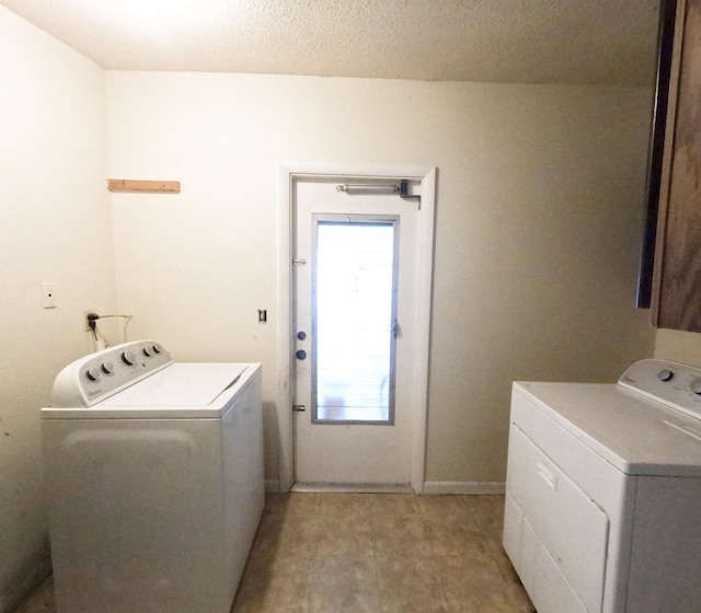 clothes washing area with laundry area, baseboards, washer and clothes dryer, and a textured ceiling