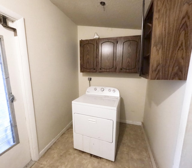 laundry room featuring a textured ceiling, washer / clothes dryer, cabinet space, and baseboards