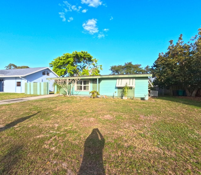 view of front of home featuring driveway, fence, and a front lawn