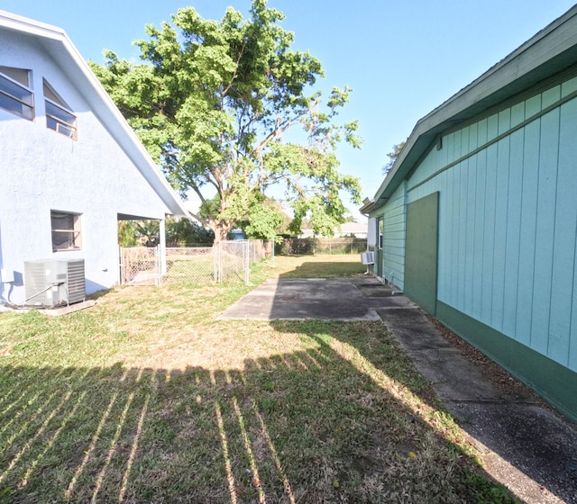 view of yard with a patio, cooling unit, fence, and central air condition unit