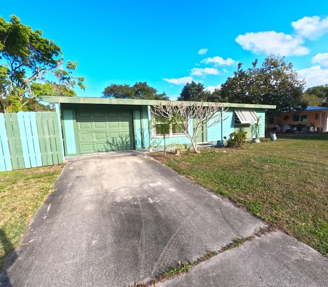 ranch-style house featuring a front yard, driveway, an attached garage, and fence