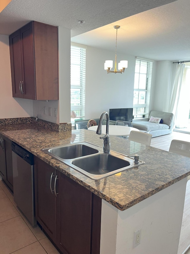 kitchen featuring dishwasher, open floor plan, a sink, and a textured ceiling