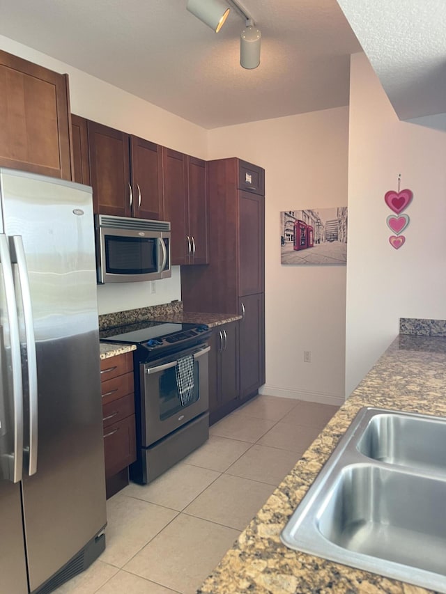 kitchen featuring appliances with stainless steel finishes, light tile patterned flooring, and a sink