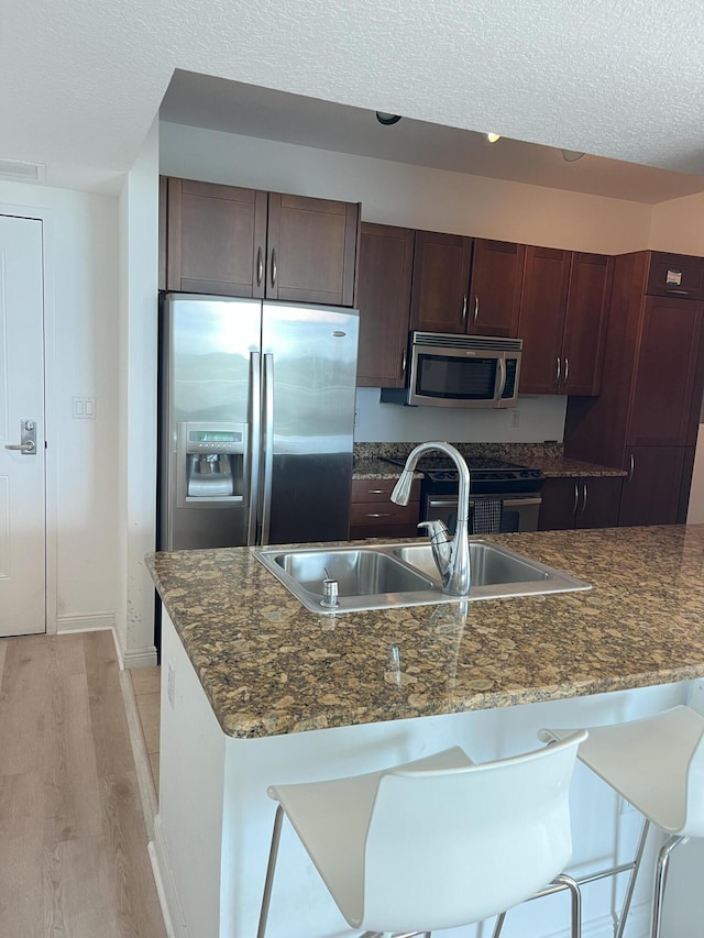 kitchen featuring visible vents, appliances with stainless steel finishes, a textured ceiling, light wood-style floors, and a sink