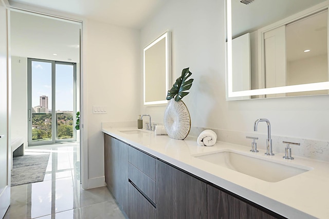 full bath featuring a sink, a wall of windows, double vanity, and tile patterned floors