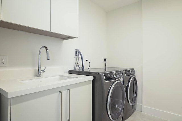 clothes washing area featuring baseboards, cabinet space, independent washer and dryer, and a sink