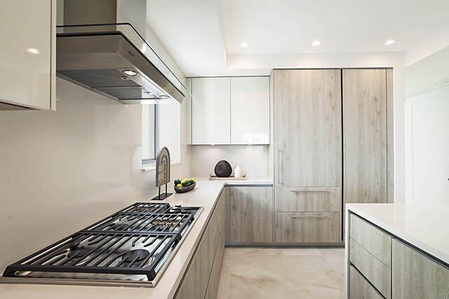 kitchen featuring modern cabinets, ventilation hood, stainless steel gas stovetop, white cabinets, and light countertops