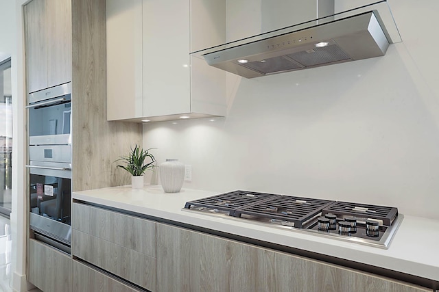 kitchen with light countertops, wall chimney range hood, and modern cabinets