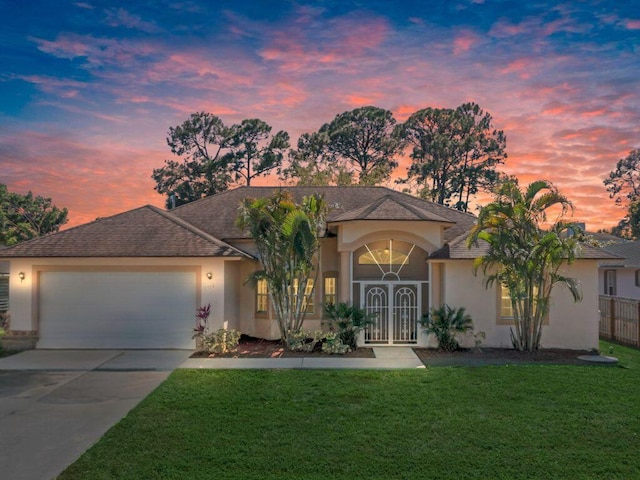 ranch-style home featuring stucco siding, concrete driveway, an attached garage, a front yard, and fence