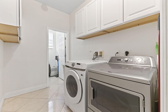 laundry area with light tile patterned floors, washing machine and dryer, cabinet space, and baseboards