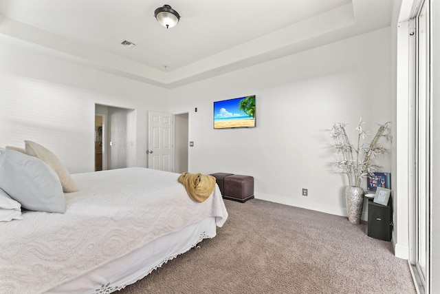 carpeted bedroom featuring visible vents, baseboards, and a raised ceiling