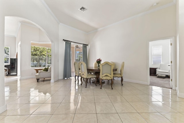 dining room featuring light tile patterned floors, arched walkways, visible vents, baseboards, and ornamental molding