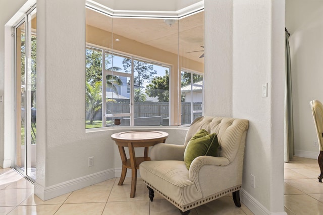 living area featuring a ceiling fan, tile patterned flooring, and baseboards