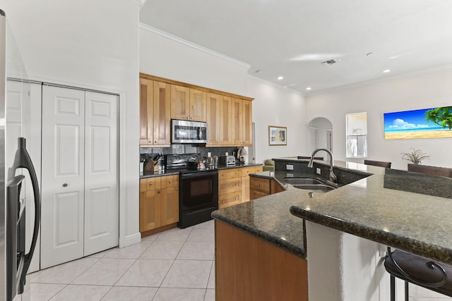 kitchen with arched walkways, stainless steel appliances, backsplash, light tile patterned flooring, and a sink