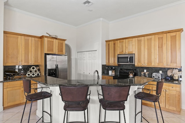 kitchen featuring light tile patterned floors, appliances with stainless steel finishes, arched walkways, and ornamental molding