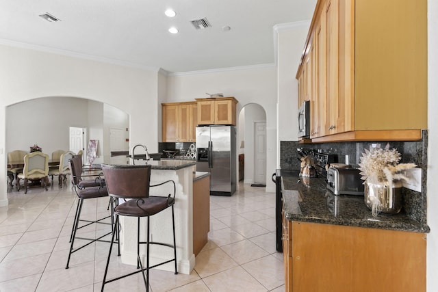 kitchen with visible vents, a kitchen bar, arched walkways, and stainless steel appliances