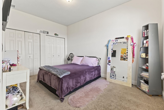 carpeted bedroom featuring baseboards and multiple closets