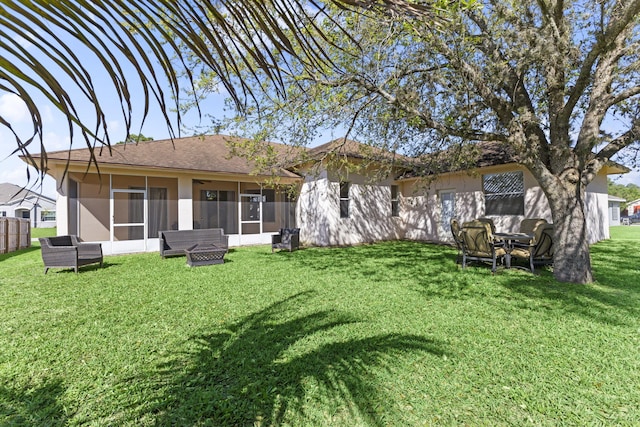 rear view of house with a yard, a sunroom, and stucco siding