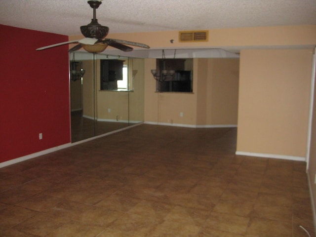 unfurnished room featuring baseboards, visible vents, a textured ceiling, and a ceiling fan