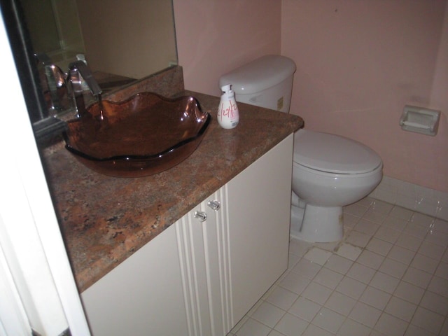 half bath with vanity, tile patterned floors, and toilet