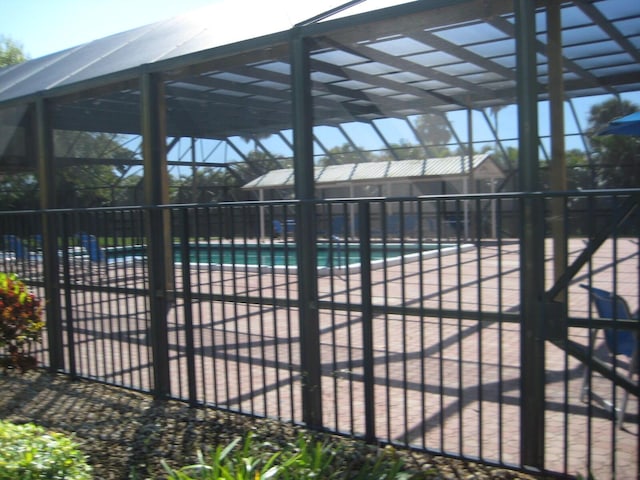 view of pool with glass enclosure, a patio, a fenced in pool, and fence