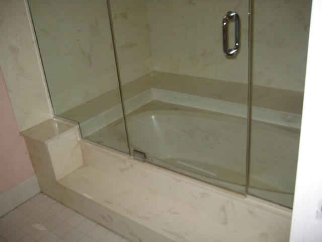 full bath featuring tile patterned floors and a marble finish shower